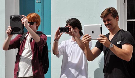 Three people holding mobile devices at eye level to look at images